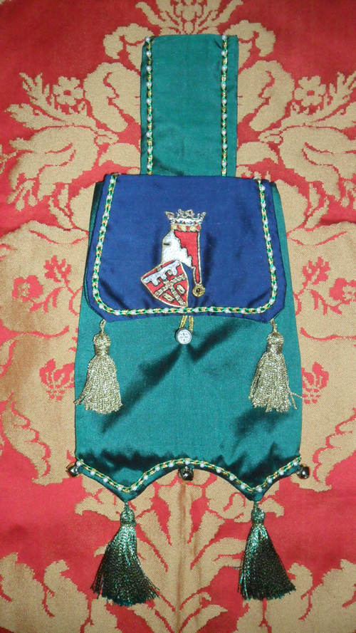 Blue and Green Silk Pouch depicting a miniature Ancient Heraldic device for the first born son of Sir Justyn in Goldwork . Helm in Silver leather with Silk Mantle. Duke's Coronet in Gold Kid leather